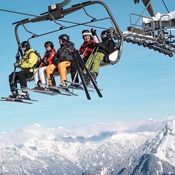Spurwechsel in die weiße Zeit Skifahrer im Sessellift vor verschneitem Bergpanorama im Brandnertal in Vorarlberg während des Winterurlaubs.