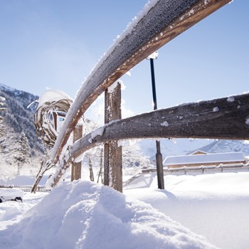 Verschneite Winterlandschaft mit Holzgeländer und Bergblick beim Hotel im Brandnertal in Vorarlberg.