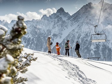 Skifahrergruppe auf verschneiter Piste in Brand in Vorarlberg mit Bergpanorama und Sessellift im Hintergrund.